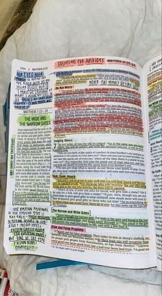 an open book with colorful text on it sitting on top of a white sheeted surface