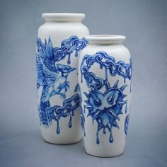 two blue and white vases sitting next to each other on a gray background,