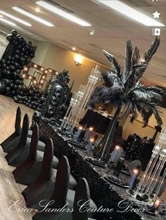 a table set up with black and white decorations, candles and palm tree centerpieces