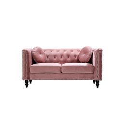 a pink velvet couch with studding on the arms and back, against a white background