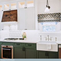 a kitchen with green cabinets and white counter tops is pictured in this image, there are two windows above the sink