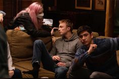 a group of people sitting on top of a couch in front of a woman with pink hair