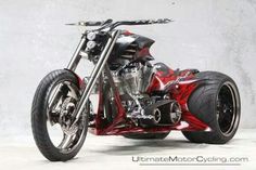 a red and black motorcycle parked on top of a white floor next to a wall