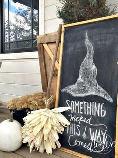 a chalkboard sign sitting on top of a wooden floor next to a white pumpkin