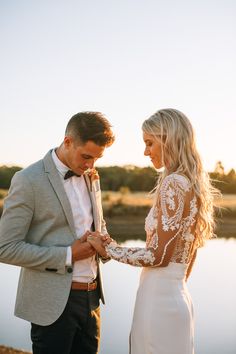 a man and woman standing next to each other in front of a body of water