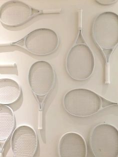 several tennis rackets lined up against a white wall