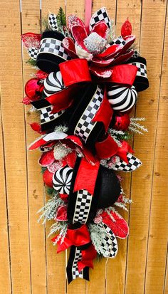 a red and black wreath hanging on the side of a wooden fence