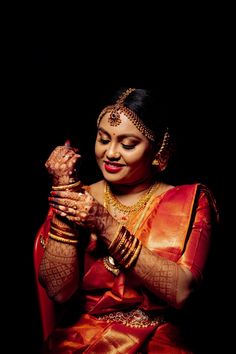 a woman in an orange sari is holding her hands together