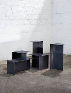 three black tables sitting next to each other in front of a white brick wall and floor