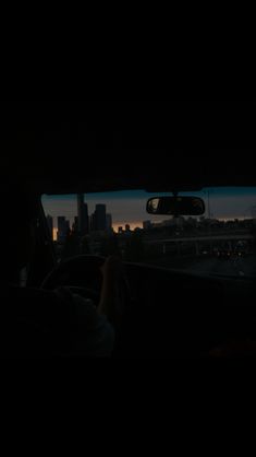 the view from inside a car at night with city lights and buildings in the background