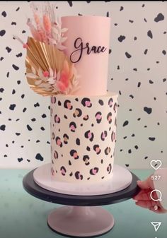 two tiered cake decorated with pink and black leopard print, gold foil fan and name on top