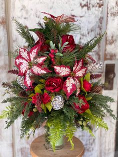 a vase filled with red flowers and greenery