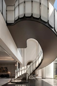 a spiral staircase in an office building with glass panels on the walls and flooring