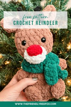 a hand holding a crochet reindeer ornament in front of a christmas tree