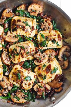 a pan filled with mushrooms and spinach on top of a wooden table