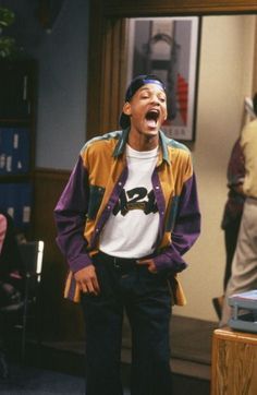 the young man is laughing while standing in front of an open door with his mouth wide open