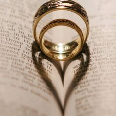 two wedding rings casting a heart shape on top of an open book with the words love cher