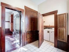 an empty kitchen with wooden cabinets and white appliances in the corner, while another door is open to reveal a washer and dryer