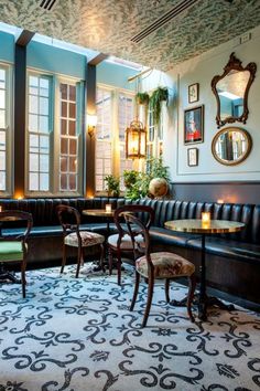 a restaurant with tables and chairs in front of large windows, decorated with ornate wallpaper