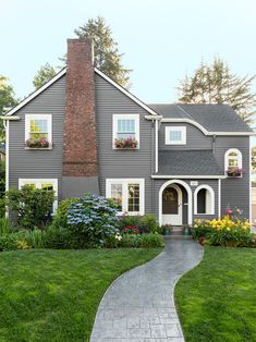 a gray house with white trim and flowers in the window boxes on the front door