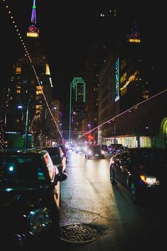 a city street filled with lots of traffic and tall buildings in the background at night