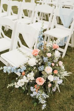 a bunch of white chairs sitting on top of a grass covered field next to each other