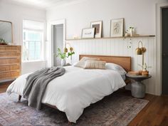 a bedroom with white walls and wood floors has a large bed that is made up