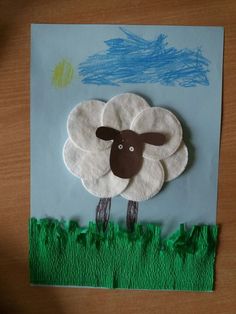 a sheep made out of felt sitting on top of a piece of paper with grass