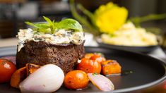 a black plate topped with meat and vegetables