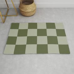 a green and white checkered rug on the floor next to a basket with a plant in it