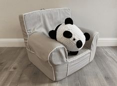 a stuffed panda bear sitting on top of a gray chair