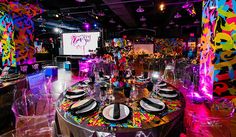 a large party setup with neon lights and black plates, silverware and napkins