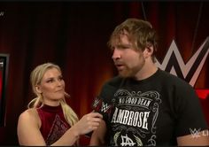 a man and woman standing next to each other in front of a red curtain with the wwe logo on it