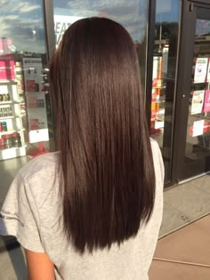 the back of a woman's head with long brown hair in front of a store