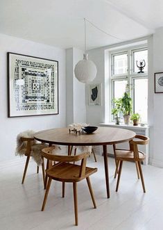 a dining room table with chairs and pictures on the wall in front of it's windows