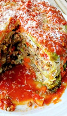 a white plate topped with an eggplant and tomato lasagna roll covered in sauce