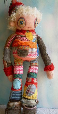 a stuffed animal doll with multicolored clothing on it's face and legs