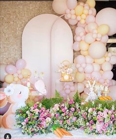 a table topped with lots of balloons and flowers next to a giant balloon arch in the background