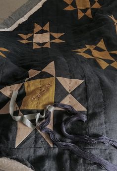 an old quilt is laying on the floor with some tassels hanging from it