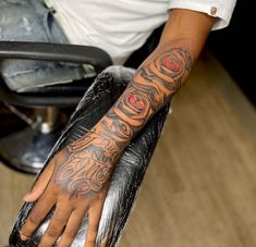 a man with a tattoo on his arm is sitting in a barbershop and holding onto the chair