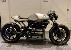 a bmw motorcycle parked in a garage next to a white brick wall and black tire rims