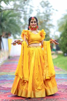 a woman in a yellow outfit is standing on a colorful carpet with her arms outstretched