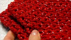 someone is crocheting a red piece of yarn