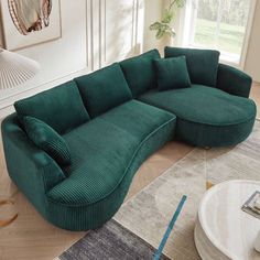 a large green couch sitting on top of a wooden floor next to a table and chair