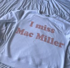 a white sweatshirt with the words i miss mac miller on it sitting on a bed