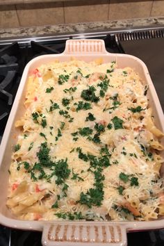 a casserole dish filled with pasta and parsley on top of an oven