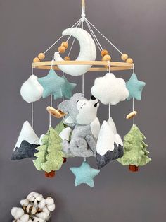 a teddy bear is hanging from a mobile with stars and moon decorations on the strings