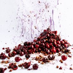 a pile of cherries sitting on top of a white table next to a wall