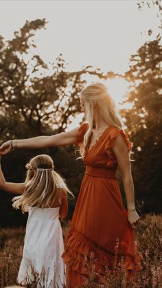 mother and daughter holding hands in field at sunset