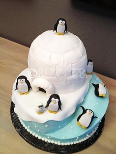 there is a cake with penguins on it and an igloose in the middle